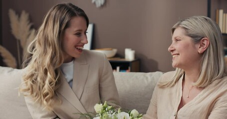 Mother's Day. A young woman comes to mother with a bouquet of flowers. The senior citizen thanks her is delighted surprised she smells the beautiful bouquet and kisses her daughter on the cheek.