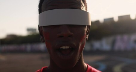 African red sport fan watching using futuristic augmented reality glasses during football match out of the stadium - Powered by Adobe