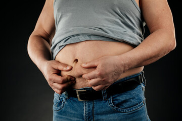 a fat man checking his weight on a black background.