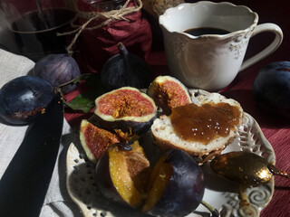 Breakfast variant with butterbroads and fruits such as plums, figs and homemade bread and figs jam and coffee. Natural light used only