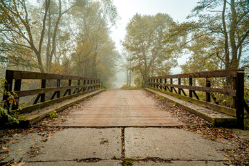 Most drewniany na rzece Szotkówka w Jastrzębiu-Zdroju na Śląsku w Polsce, jesienią w mglisty poranek. - obrazy, fototapety, plakaty