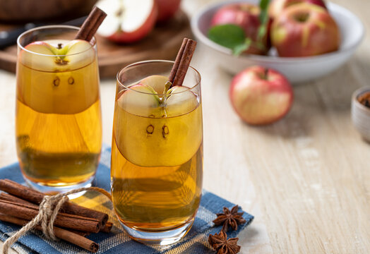 Two Glasses Of Apple Cider With Sliced Apples And Cinnamon