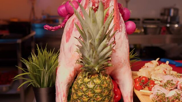 Full size raw lamb meat on table with knife in it and pineapple for decor. Displayed raw lamb body for sale.