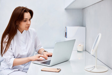 female doctor in white medical uniform using laptop