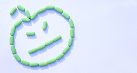 Pharmaceutical medicine pills on white background, concept Halloween day. Pumpkin with a face made of green pills