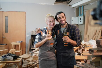 Happy Couple Carpenters have celeabate with a drink bottle after work of Assembling Furniture, Small business in wood DIY workplace office background