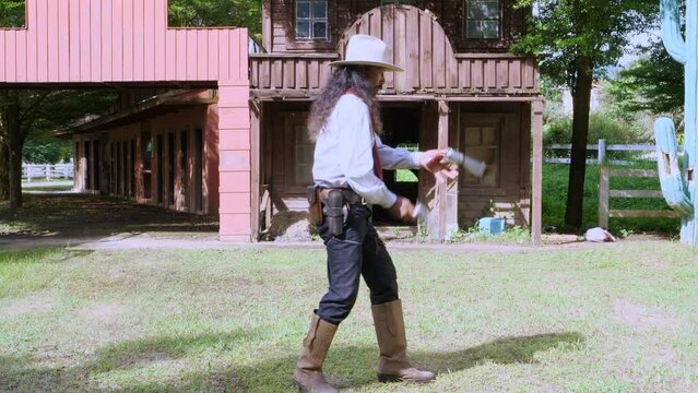 Adult Man cowboy wielding  gun Carry and store into the gun holster at the waist in vintage cowboys village background. Cowboy 1800's Concept