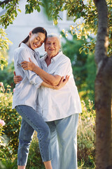 Conception of love to a parent. Young woman is with her senior mother is in the garden