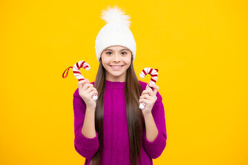 Teenager child in winter knitted hat and sweater having over yellow background.