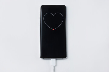 Smartphone on charge showing battery charge in the form of a heart