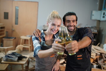 Happy Couple Carpenters have celeabate with a drink bottle after work of Assembling Furniture, Small business in wood DIY workplace office background