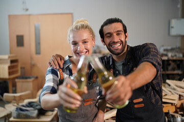 Happy Couple Carpenters have celeabate with a drink bottle after work of Assembling Furniture, Small business in wood DIY workplace office background