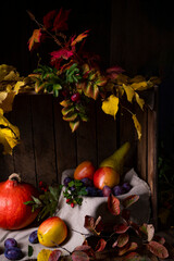 Various fruits in a wooden box with autumn leaves