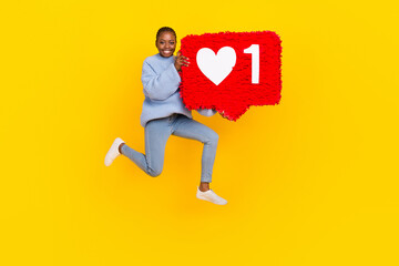 Full legth photo of young popular lady jumping air holding big red heart social media isolated on yellow color background