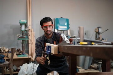 Contemporary Carpenter Working, Portrait of modern carpenter making wood furniture while working in joinery lit by sunlight with factory background on small business concept, copy space