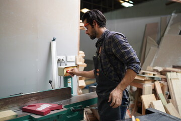 Contemporary Carpenter Working, Portrait of modern carpenter making wood furniture while working in joinery lit by sunlight with factory background on small business concept, copy space