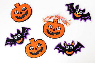 Halloween DIY and kids creativity. felt pumpkins and bats on white background. top view