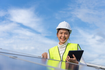 Beautiful Asian female engineer uses a black tablet to inspect solar power station, Clean energy.