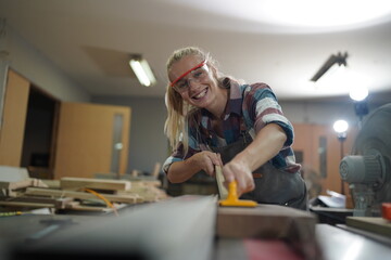 Contemporary Carpenter Working, Portrait of modern carpenter making wood furniture while working in joinery lit by sunlight with factory background on small business concept, copy space