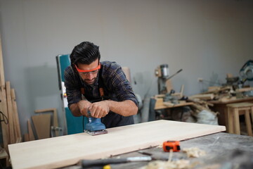 Contemporary Carpenter Working, Portrait of modern carpenter making wood furniture while working in joinery lit by sunlight with factory background on small business concept, copy space