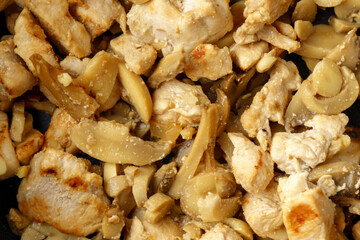 Chopped chicken fillet with mushroom fried on frying pan. Cooking process close up.