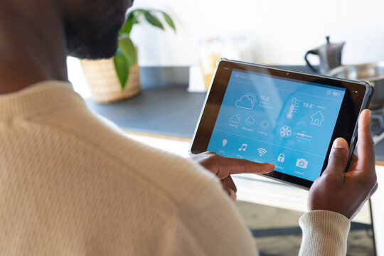 Midsection of african american man using tablet with weather forecast