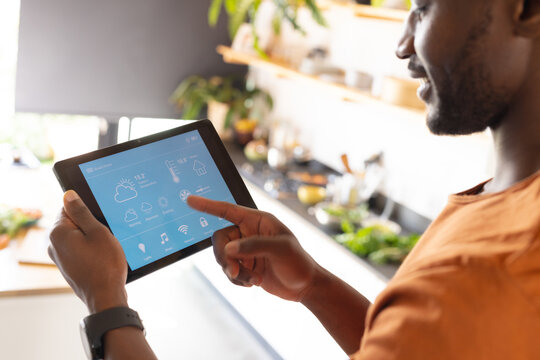 Happy african american man using tablet with weather forecast - Powered by Adobe