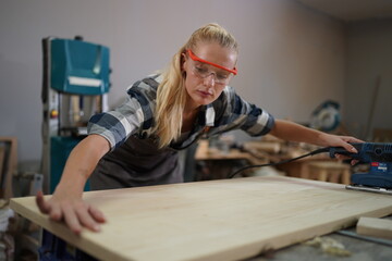 Contemporary Carpenter Working, Portrait of modern carpenter making wood furniture while working in joinery lit by sunlight with factory background on small business concept, copy space