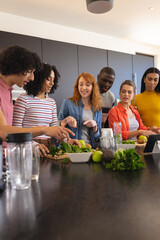 Happy diverse friends cooking together and smiling in kitchen