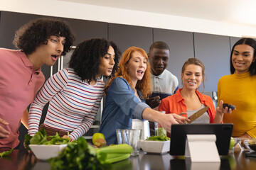 Happy diverse friends cooking together and using tablet in kitchen