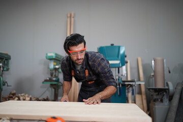 Contemporary Carpenter Working, Portrait of modern carpenter making wood furniture while working in joinery lit by sunlight with factory background on small business concept, copy space