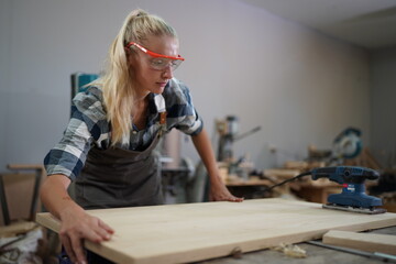 Contemporary Carpenter Working, Portrait of modern carpenter making wood furniture while working in joinery lit by sunlight with factory background on small business concept, copy space