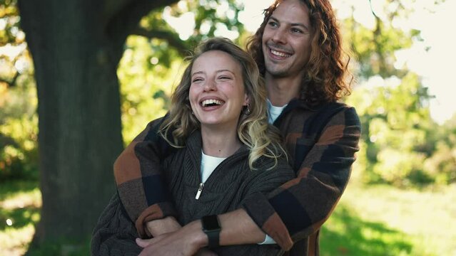 Funny young couple hugging and looking at each other in the park outdoors
