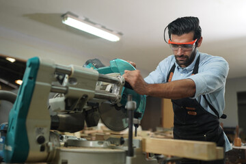 Contemporary Carpenter Working, Portrait of modern carpenter making wood furniture while working in joinery lit by sunlight with factory background on small business concept, copy space