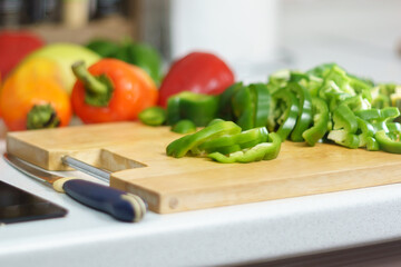 Cutting green bell pepper, cooking, food and home concept. Cutting board at home