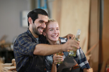 Happy Couple Carpenters have celeabate with a drink bottle after work of Assembling Furniture, Small business in wood DIY workplace office background