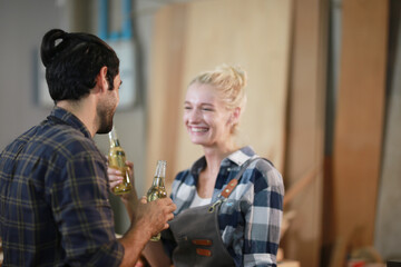 Happy Couple Carpenters have celeabate with a drink bottle after work of Assembling Furniture, Small business in wood DIY workplace office background