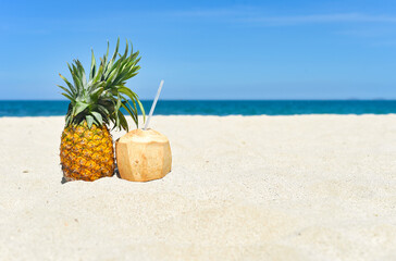 Pineapple and coconut drink on white sand beckground