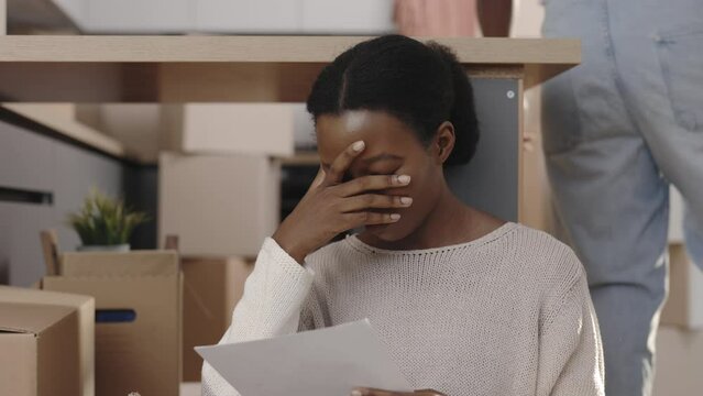 African american woman feeling sad because of the bills they need to paid. Female desperate because they need to relocate from their new home. People and eviction notice concept.