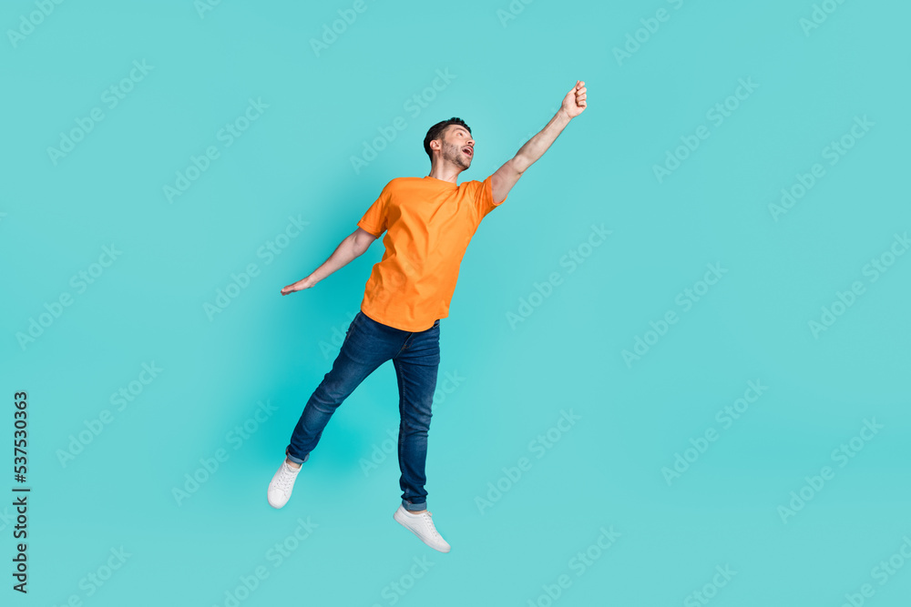 Poster Full body photo of positive person raise arm hold empty space banner look up wear orange clothes jeans isolated on cyan color background