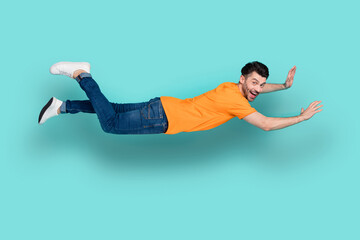 Full length photo of crazy guy levitating in air wind isolated on cyan color background