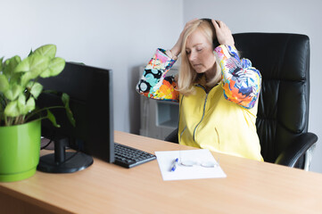 Mature businesswoman suffering from headache in front of computer at office desk