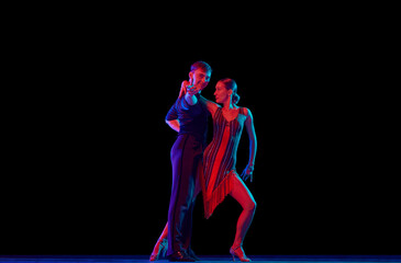 Fototapeta na wymiar Two dancing people, ballroom dancers in elegance outfits in motion, action over dark background in neon light. Concept of art, music, dance, emotions.