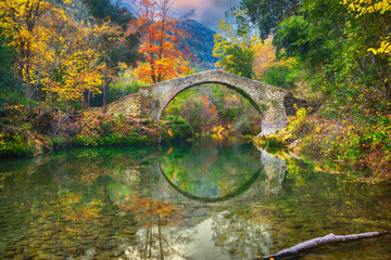 Pont des Tuves - the ancient roman stone bridge across the Siagne river surrounded by yellow autumn forest near Saint-Cezaire-sur-Siagne, Alpes Maritimes, France