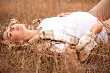 The beautiful pregnant woman posing over autumn background.