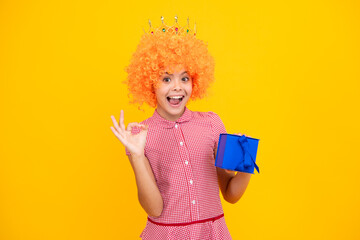 Amazed teen girl. Child with gift present box on isolated studio background. Gifting for kids birthday. Excited expression, cheerful and glad.
