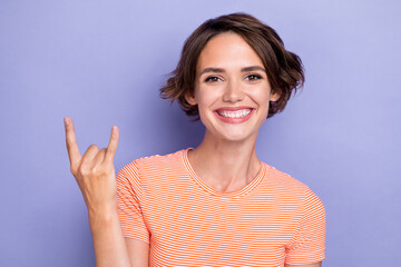 Closeup photo of young pretty excited funny face woman wear pink t-shirt toothy smile good mood showing rock sign isolated on pastel purple color background