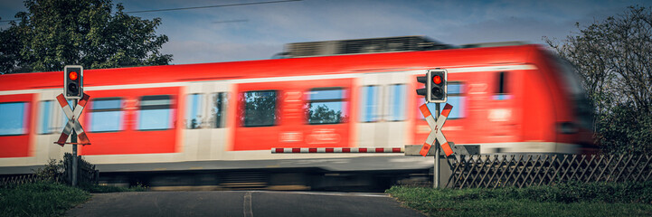 Zug fährt über Bahnübergang mit geschlossener Bahnschranke