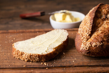 Bread with butter on wooden board. Closeup view