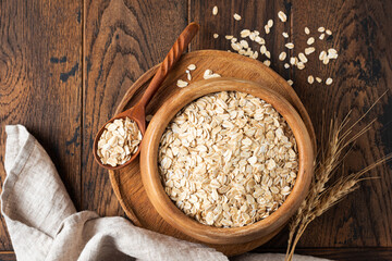 Rolled oats, oat flakes in wooden bowl